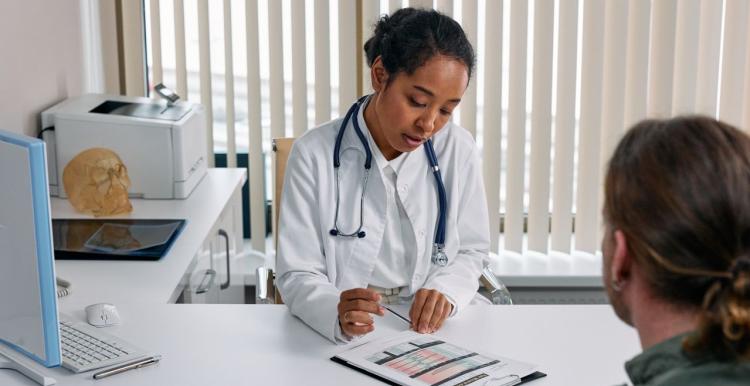 A doctor consulting with a patient in an office, discussing a medical chart. 