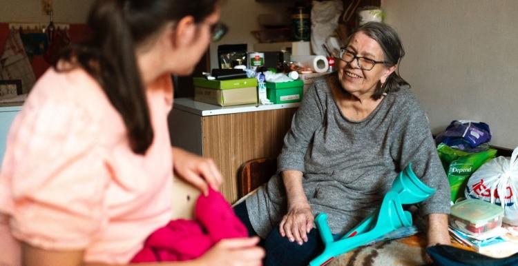 A caregiver helps a senior woman with a crutch