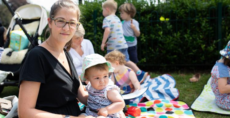 Woman sitting on a picnic blanket with her baby Woman sitting on a picnic blanket with her baby