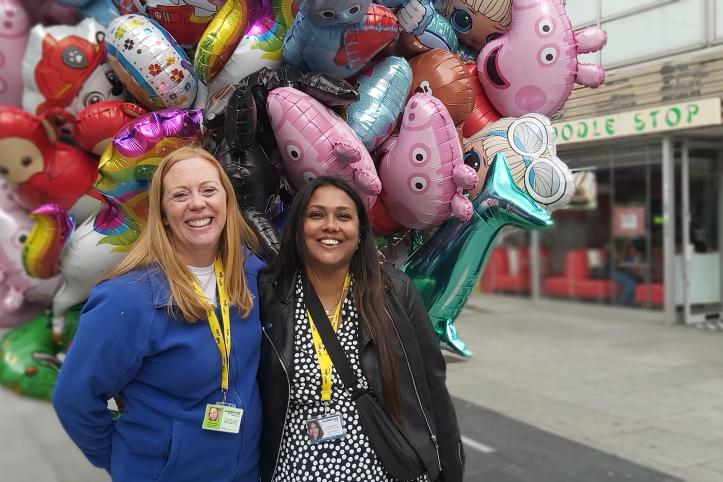 2 Healthwatch staff members standing in front of balloons
