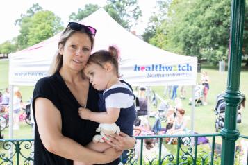 Mother holding her daughter on her hip at a Healthwatch event 