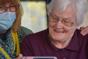 carer looking at phone together with elderly woman