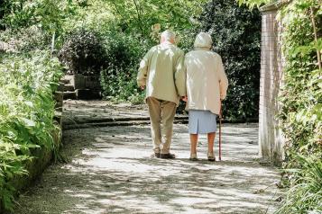 two elderly people walking in a park