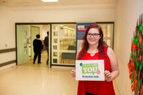 Image of volunteer in a hospital holding a sign "It starts with you"
