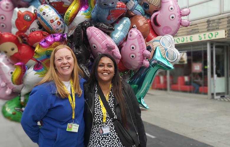 2 Healthwatch staff members standing in front of balloons
