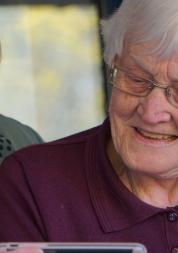 carer looking at phone together with elderly woman